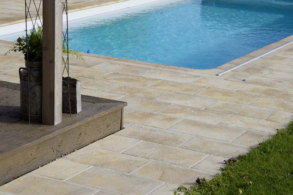 Foto: Terrasse in Holz kombiniert mit Semmelrock Bradstone Travero-Platten rund um den Pool.