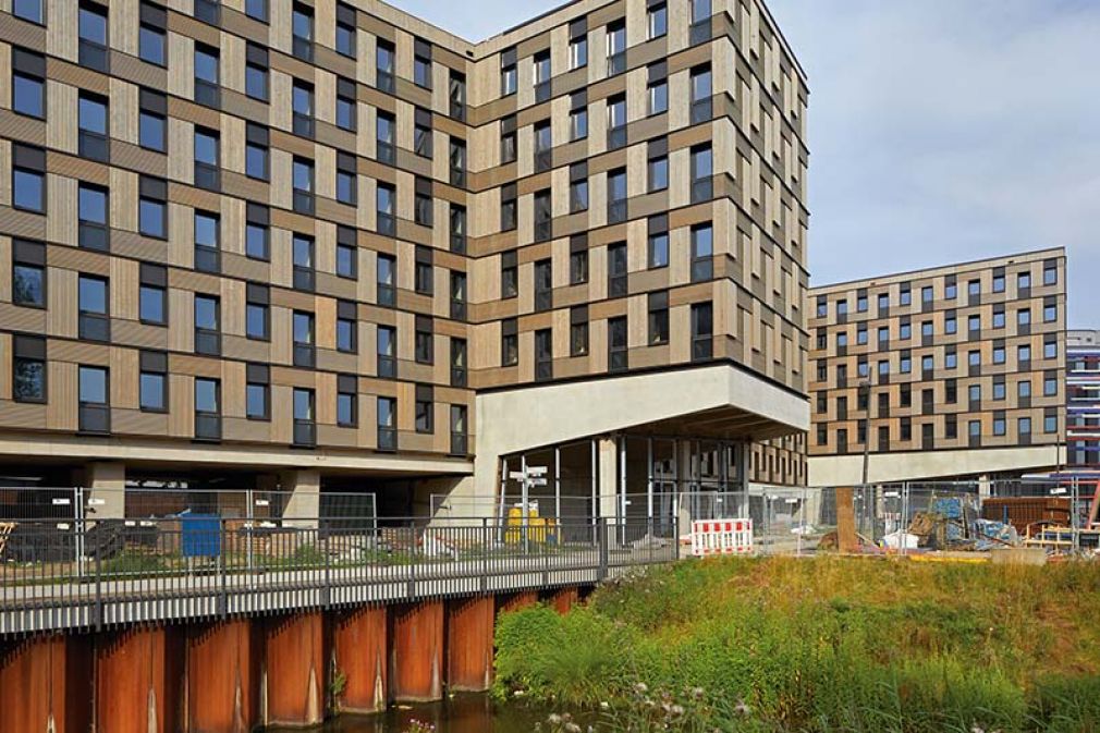 Foto: Das Studentenwohnheim Woodie in Hamburg wurde in Modulbauweise errichtet. Sämtliche Module wurden komplett mit Inneneinrichtung, fertigen Bädern, Fenstern und Türen vorgefertigt, zwischengelagert, just in time nach Hamburg geliefert und dort mit einem Kran an die richtige Position gehoben.