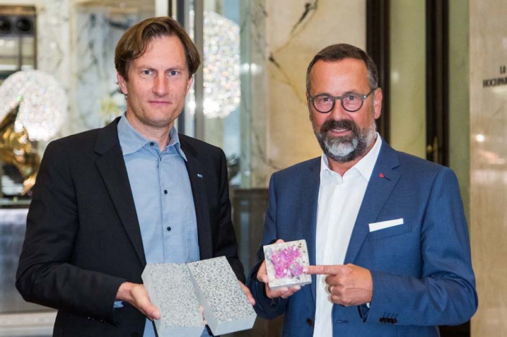 Foto:   Sebastian Spaun (links) und Rudolf Zrost (rechts) zeigen anhand eines Probewürfels die Carbonatisierung von Beton.